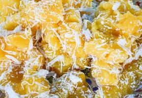 dessert thaï cuit à la vapeur gâteau de manioc jaune avec noix de coco râpée photo