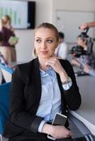 portrait d'une jeune femme d'affaires au bureau avec une équipe lors d'une réunion en arrière-plan photo