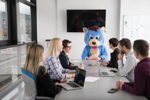 patron habillé en ours s'amusant avec des gens d'affaires dans un bureau branché