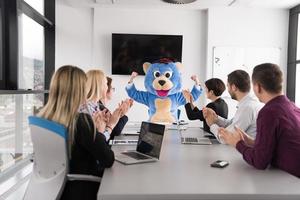 patron habillé en ours s'amusant avec des gens d'affaires dans un bureau branché photo