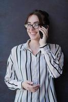 femme d'affaires de démarrage en chemise avec des lunettes à l'aide d'un téléphone portable photo