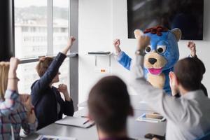 patron habillé en ours s'amusant avec des gens d'affaires dans un bureau branché photo