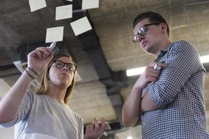 jeune couple à l'intérieur d'un bureau moderne écrivant des notes sur des autocollants photo