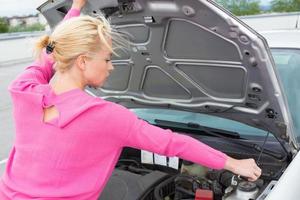 femme inspectant le moteur de la voiture cassée.