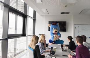 patron habillé en ours s'amusant avec des gens d'affaires dans un bureau branché photo