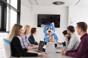 patron habillé en ours s'amusant avec des gens d'affaires dans un bureau branché photo