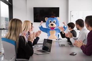 patron habillé en ours s'amusant avec des gens d'affaires dans un bureau branché photo