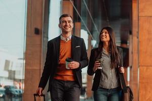 homme d'affaires et femme d'affaires parlant et tenant des bagages voyageant en voyage d'affaires, transportant du café frais dans leurs mains. concept d'entreprise photo