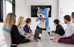 patron habillé en ours s'amusant avec des gens d'affaires dans un bureau branché photo