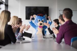 patron habillé en ours s'amusant avec des gens d'affaires dans un bureau branché photo