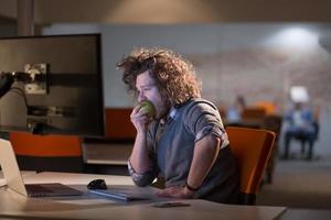 homme qui mange une pomme dans son bureau photo