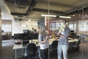 jeune couple à l'intérieur d'un bureau moderne écrivant des notes sur des autocollants photo