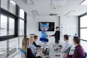 patron habillé en ours s'amusant avec des gens d'affaires dans un bureau branché photo