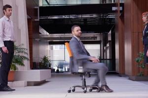 homme d'affaires assis sur une chaise de bureau, groupe de personnes passant par photo