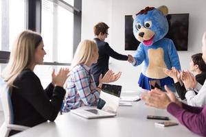 patron habillé en ours s'amusant avec des gens d'affaires dans un bureau branché photo