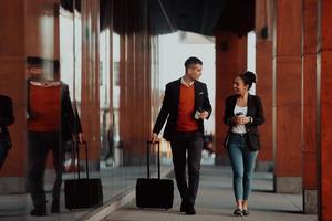 homme d'affaires et femme d'affaires parlant et tenant des bagages voyageant en voyage d'affaires, transportant du café frais dans leurs mains. concept d'entreprise photo