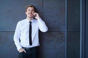 homme d'affaires de démarrage dans une chemise blanche avec une cravate à l'aide d'un téléphone portable photo