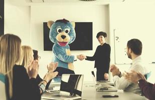 patron habillé en ours s'amusant avec des gens d'affaires dans un bureau branché photo