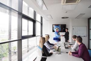 patron habillé en ours s'amusant avec des gens d'affaires dans un bureau branché photo