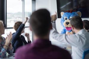 patron habillé en ours s'amusant avec des gens d'affaires dans un bureau branché photo