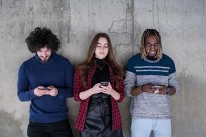 équipe commerciale multiethnique décontractée utilisant des téléphones portables devant un mur de béton photo