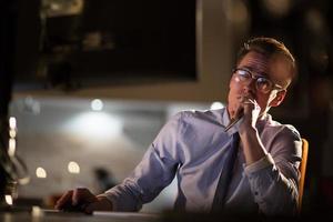 homme travaillant sur ordinateur dans un bureau sombre photo