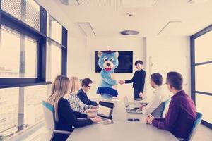 patron habillé en ours s'amusant avec des gens d'affaires dans un bureau branché photo