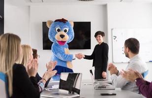 patron habillé en ours s'amusant avec des gens d'affaires dans un bureau branché photo