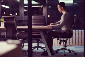 homme travaillant sur un ordinateur portable dans un bureau sombre photo