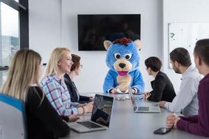 patron habillé en ours s'amusant avec des gens d'affaires dans un bureau branché photo