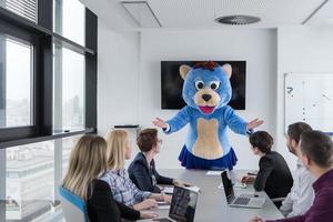 patron habillé en ours s'amusant avec des gens d'affaires dans un bureau branché photo