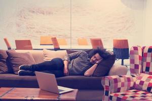 homme dormant sur un canapé dans un bureau créatif photo