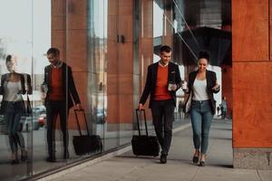 homme d'affaires et femme d'affaires parlant et tenant des bagages voyageant en voyage d'affaires, transportant du café frais dans leurs mains. concept d'entreprise photo