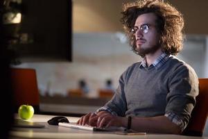 homme travaillant sur ordinateur dans un bureau sombre photo