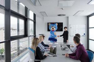 patron habillé en ours s'amusant avec des gens d'affaires dans un bureau branché photo