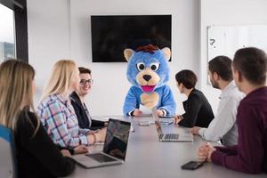 patron habillé en ours s'amusant avec des gens d'affaires dans un bureau branché photo