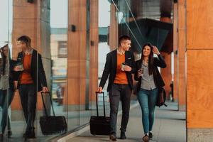 homme d'affaires et femme d'affaires parlant et tenant des bagages voyageant en voyage d'affaires, transportant du café frais dans leurs mains. concept d'entreprise photo