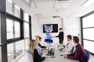 patron habillé en ours s'amusant avec des gens d'affaires dans un bureau branché photo