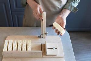 une femme fabrique du savon naturel fait à la main.le savon fini est coupé en morceaux à l'aide d'une machine spéciale. spa à domicile. petite entreprise photo