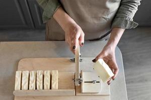 une femme fabrique du savon naturel fait à la main.le savon fini est coupé en morceaux à l'aide d'une machine spéciale. spa à domicile. petite entreprise photo
