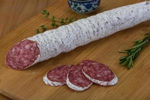 Saucisse fuet sur planche de bois et fond de bois photo