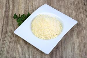 Parmesan râpé dans un bol sur fond de bois photo