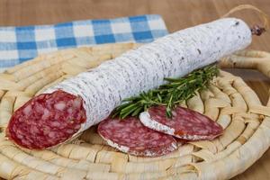 Saucisse fuet sur planche de bois et fond de bois photo