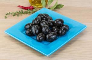 olives noires sur la plaque et fond en bois photo