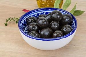 olives noires dans un bol sur fond de bois photo