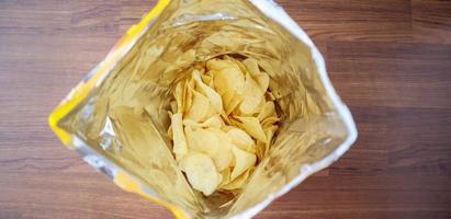 Chips de pommes de terre dans un sac à collation ouvert en gros plan sur le sol de la table photo