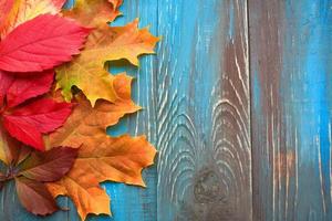 cadre de feuilles d'automne colorées sur fond de bois bleu et marron photo