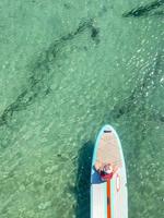 petite fille sur le devant d'un paddle board sur l'océan photo