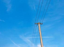 lignes électriques de poteau électrique fils électriques sortants contre le ciel bleu nuageux. photo