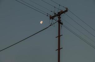 lignes électriques sur fond de ciel du soir et de lune. photo